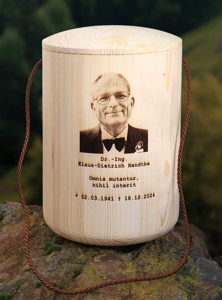eine Urne aus Holz mit graviertem Foto des Verstorbenen und seinen Lebensdaten